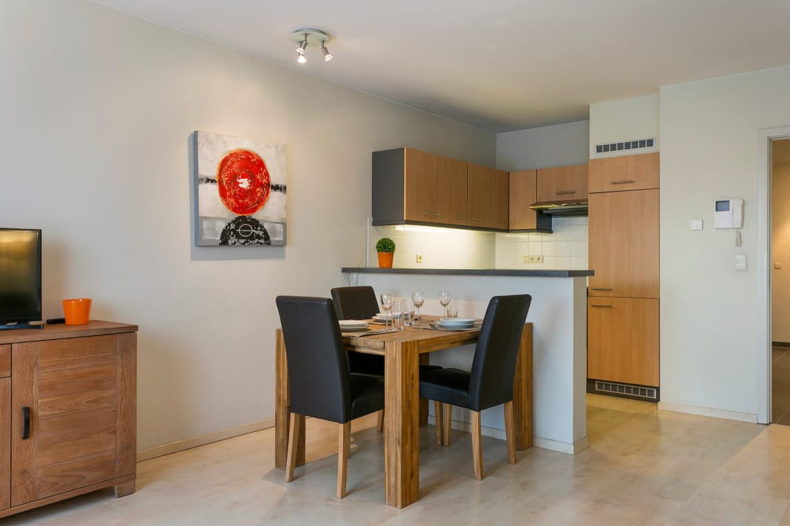 dining table and fully equipped kithcen with artwork on wall in serviced apartment