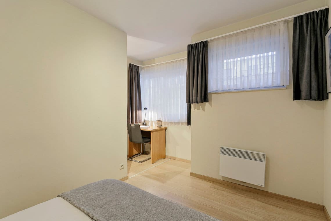 double bed with linen provided in serviced apartment with office desk