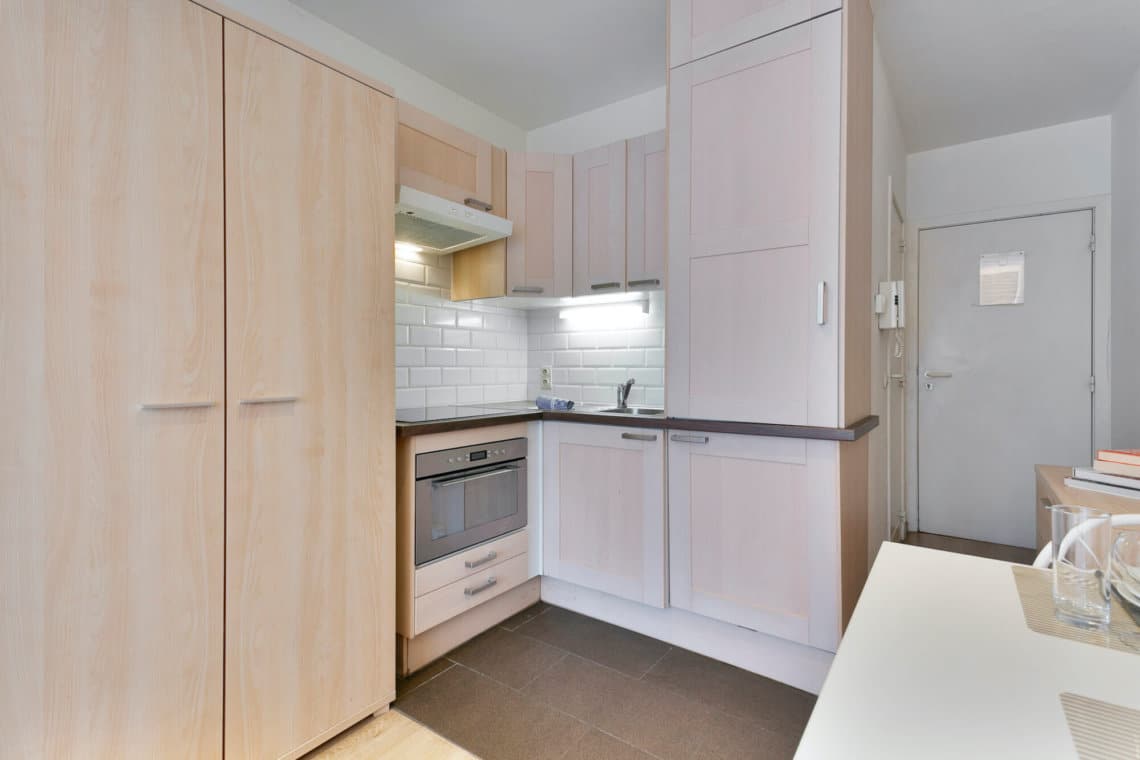 fully equipped kitchen with cupboard storage in furnished studio apartment in european quarter